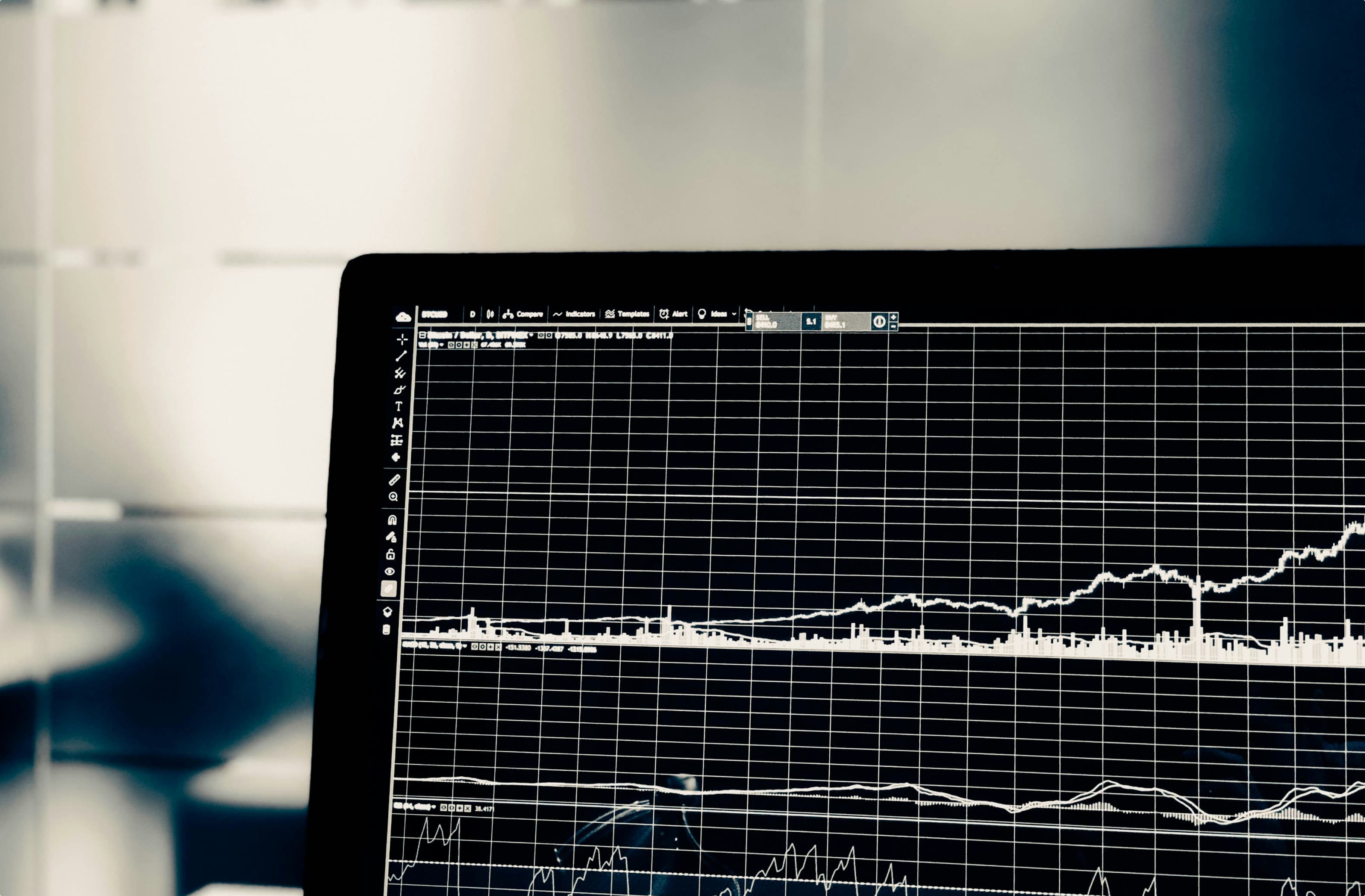 Close-up of a laptop screen displaying stock market charts and data, with a dark background.
